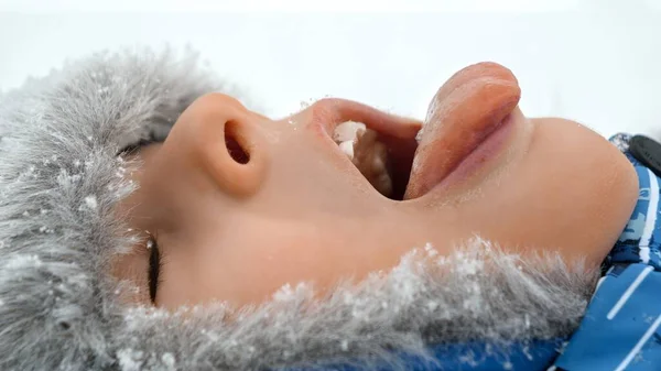 Portret Chłopca Leżącego Zaśnieżonym Parku Łapiącego Płatki Śniegu Językiem Uśmiechającego — Zdjęcie stockowe