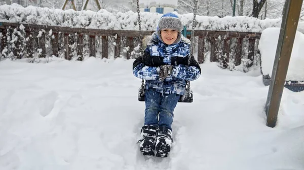 Lindo Niño Sonriente Cabalgando Columpio Patio Recreo Durante Tormenta Nieve —  Fotos de Stock