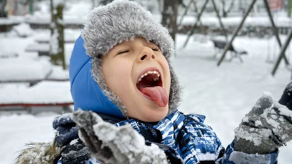 Glad Pojke Som Står Snöig Park Och Fångar Snöflingor Med — Stockfoto