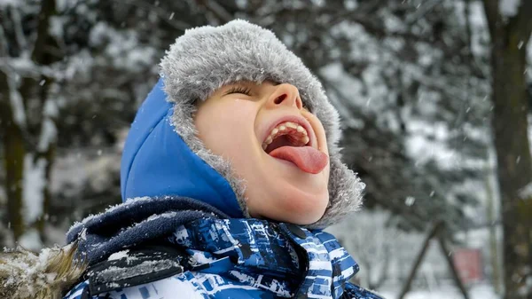Portret Chłopca Radośnie Łapiącego Płatki Śniegu Językiem Podczas Zimowych Opadów — Zdjęcie stockowe
