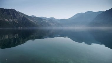 Yükselen sisli ve sisli deniz dalgalarını yansıtan yüksek dağlar.