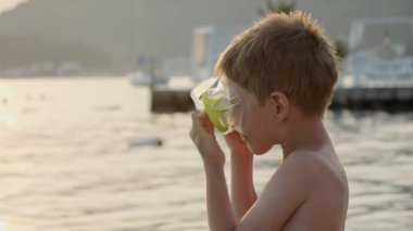 Küçük çocuk denizde yüzmeden önce şnorkel maskesi takıyor. Tatil, yaz tatili ve turizm.