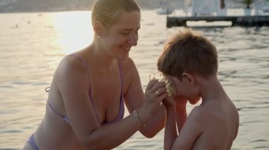 Gülümseyen genç anne, dalış ve şnorkelle yüzmek için oğlunun maskesini takmasına yardım ediyor. Tatil, yaz tatili ve turizm.