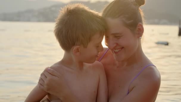 笑顔の男の子の肖像画は 日没の海岸で母親と抱擁し 楽しんでいました 夏休み 観光について — ストック動画