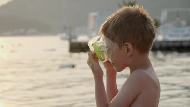 海で泳ぐ前にシュノーケリングマスクを着用する小さな少年 夏休み 観光について — ストック動画
