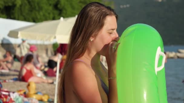 Jonge Vrouw Blaast Opblaasbare Zwemring Terwijl Bij Zonsondergang Het Strand — Stockvideo