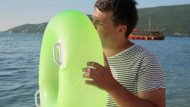 남자가 일몰에 해변에서 자신의 아이들을위한 팽창식 반지를 부풀리는 관광의 바다의 — 비디오