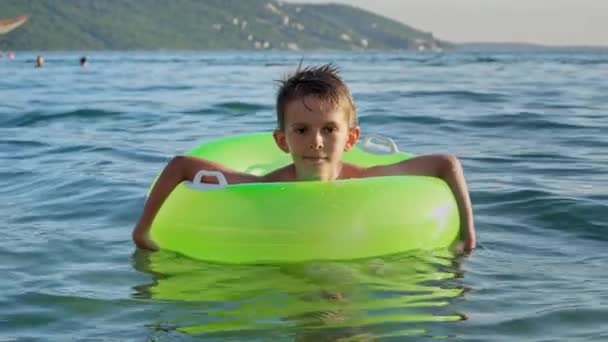 Netter Lächelnder Junge Der Aufblasbaren Ring Auf Ruhigen Wellen Schwimmt — Stockvideo