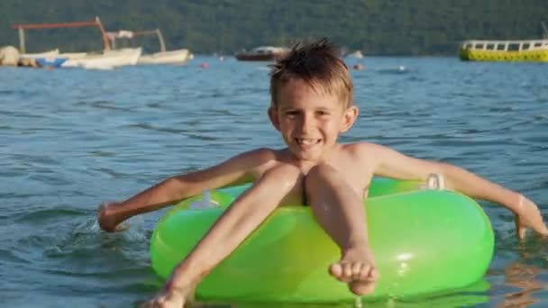 Gelukkige Lachende Jongen Zittend Groene Opblaasbare Ring Zwemmend Zee Richting — Stockvideo