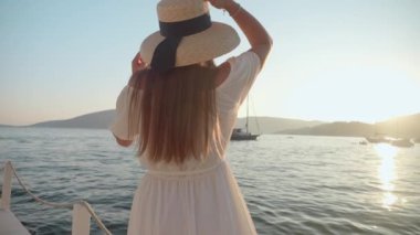 Uzun saçlı, beyaz elbiseli ve şapkalı genç bir esmer, deniz kıyısındaki ahşap bir iskelede ağır çekimde koşuyor. Turizm, yaz, tatil ve deniz kenarında tatil..