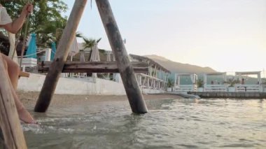 Gün batımında deniz sahili, zarif uzun elbiseli bir kadının sallanan bir salıncakta neşe bulduğu yer. Turizm, yazın huzurlu özü, özgürlük ve seyahat macerası..