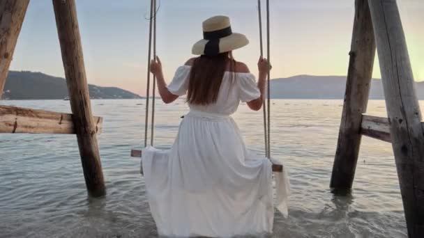 スローモーションで日没する海浜 ドレスを着た若い女性は 優しく振動し 彼女の足は海の表面に触れ 飛びつきを作成する — ストック動画