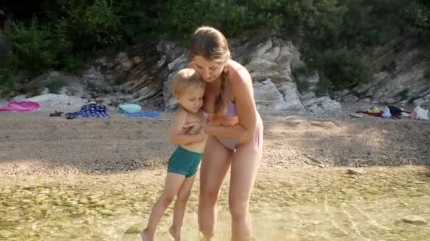 Glücklich Lächelnde Frau Bikini Hält Ihren Kleinen Sohn Und Geht — Stockvideo