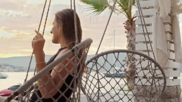 笑容满面的年轻女子 享受日落 在海滩上荡秋千 假期及海滨假期的概念 — 图库视频影像