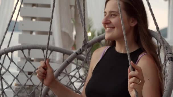 Gülümseyen Esmer Kadın Gülümsüyor Deniz Kenarındaki Barda Sallanan Yuva Sandalyesinde — Stok video