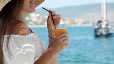Yaz tatilinin tadını çıkarırken kokteyl ya da samanla meyve suyu içen güzel bir kadın.