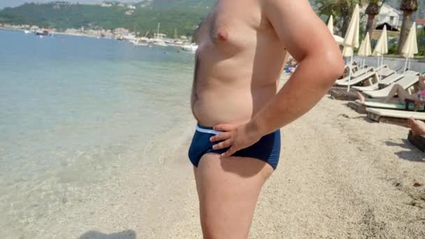 在去海滩游泳之前 大肚皮上有脂肪的年轻人把它拿着放出来 夏天前减肥的概念 — 图库视频影像