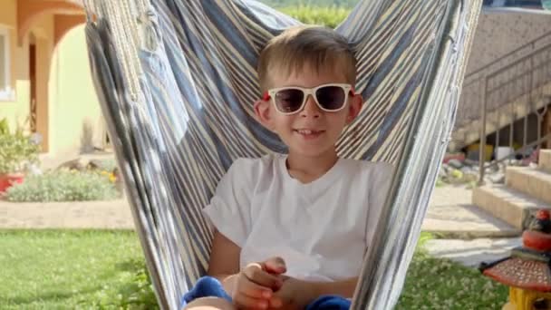 Szczęśliwy Uśmiechnięty Chłopiec Okularach Przeciwsłonecznych Huśtający Się Leżący Hamaku Ogrodzie — Wideo stockowe