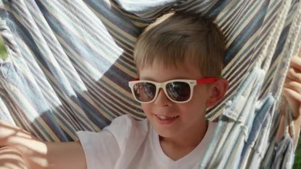 Retrato Niño Sonriente Con Gafas Sol Balanceos Salones Una Hamaca — Vídeos de Stock