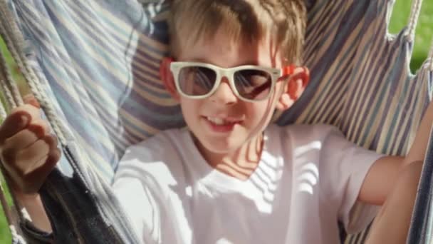 Happy Young Boy Sunglasses Enjoys Hammock Sway Garden Embodying Spirit — Stock Video