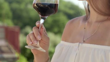 Zarif esmer kadın, balkondaki bir bardaktan ya da dağların ortasındaki villa terasından kırmızı şarap içiyor. Tatil kutlaması ve yaz tatillerinin büyüsü..