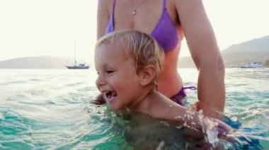 Annesinin eşlik ettiği neşeli bir çocuk olarak aile tatili, denizde yüzmeyi öğreniyor, unutulmaz yaz anıları yaratıyor..