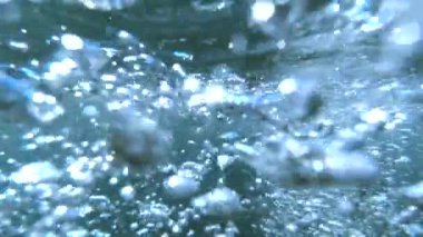 Su altı dünyasını, okyanus tabanından su yüzeyine yükselen ve güneş ışığıyla aydınlatılan hava kabarcıklarının yavaş çekim görüntüleriyle keşfedin. Soyut bir arkaplan için harika.