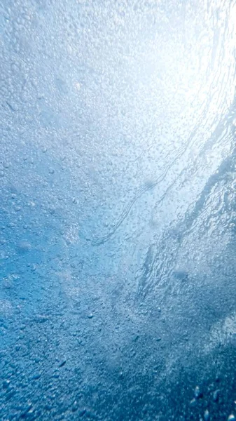 透明な青い水で海面に上昇する小さな気泡の多く — ストック写真