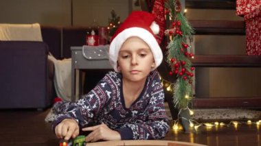 Yeni oyuncak treni ve demiryollarıyla oynayan pijamalı neşeli küçük çocuk Noel 'de hediye olarak aldı. Kış tatilinde aile kutlamaları.
