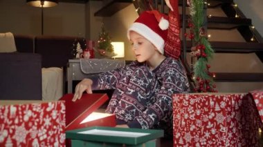 Noel Baba şapkalı küçük çocuğun portresi Noel Baba 'nın hediyeleriyle Noel hediyesi kutularını açarken heyecanlanıp mutlu oluyor. Kış tatilinde aile kutlamaları.