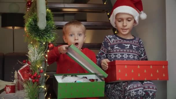 Két Kistestvér Fából Készült Lépcsőn Karácsonyi Ajándékokat Ajándékokat Bontanak Mikulástól — Stock videók