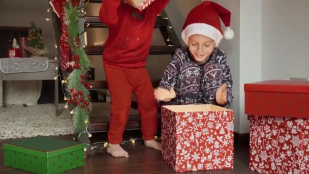 Два Милых Мальчика Пижаме Взволнованно Выглядывающие Большой Подарочной Коробке Санты — стоковое видео