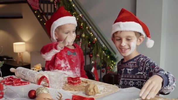 2人の陽気な少年が家でクリスマスに料理しながら小麦粉で遊んで楽しんでいます 冬休み お祝い パーティー — ストック動画