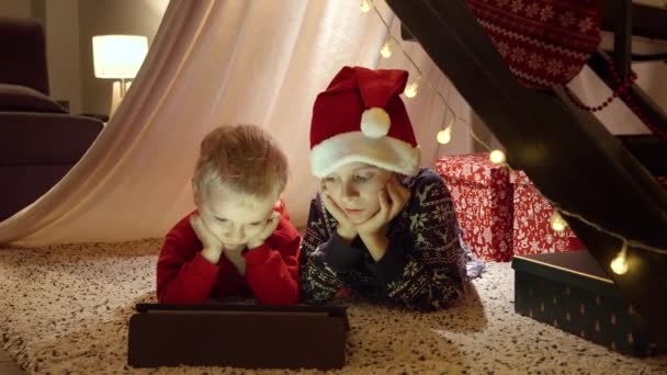 Dos Niños Noche Navidad Tumbados Suelo Casa Viendo Vídeo Tableta — Vídeo de stock
