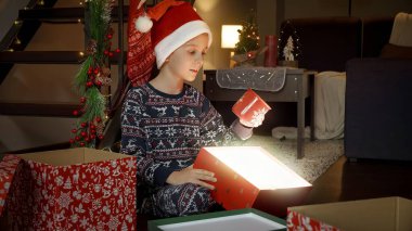 Gülümseyen neşeli çocuk Noel Baba 'dan aldığı güzel fincana bakıyor..