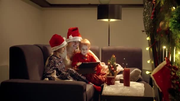 リビングルームのタブレットコンピュータでクリスマスの夜に映画を見ている幸せな家族 冬休み お祝い パーティー — ストック動画