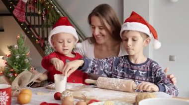 Mutlu anne, oğullarına Noel kurabiyeleri ve bisküvileri pişirmeleri için yardım ediyor. Kış tatili, kutlamalar ve parti.