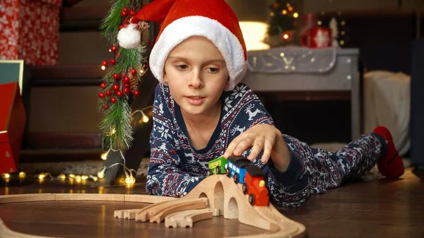 Счастливый Улыбающийся Мальчик Шляпе Санты Лежит Полу Играет Игрушечным Деревянным — стоковое фото