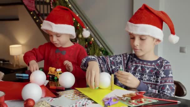 Dwóch Chłopców Czapkach Mikołaja Tradycyjne Ręcznie Dekoracje Świąteczne Bombki Zimowe — Wideo stockowe