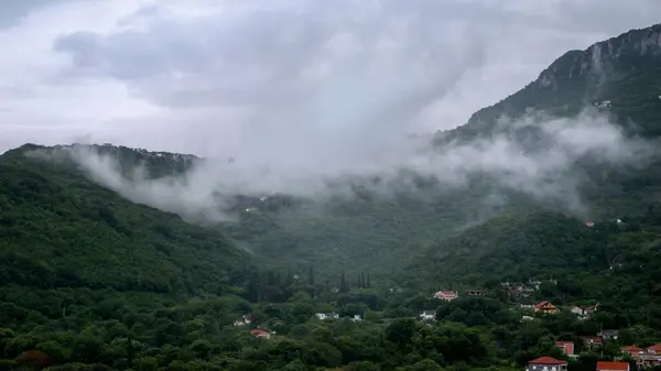 Mała Wioska Wysokich Górach Porośnięta Drzewami Pokryta Niskimi Chmurami Deszczu Zdjęcie Stockowe
