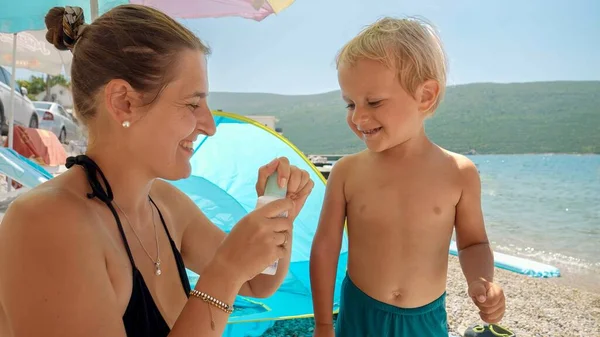 Junge Mutter Trägt Sonnenschutzspray Auf Ihren Kleinen Sohn Auf Während — Stockfoto