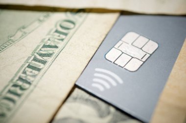 Üzerinde çip ve dolar banknotları olan gri plastik bir kredi kartını kapat.