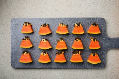 Papaya yemek tahtasında parçalar halinde duruyor.