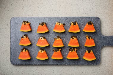 Papaya yemek tahtasında parçalar halinde duruyor.