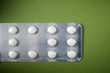 İlaç tabletleri yeşil bir masada su toplamış.