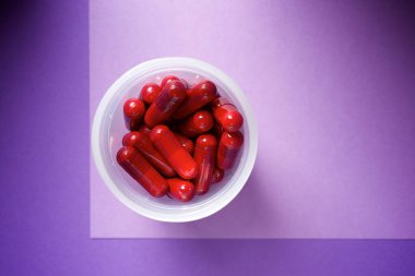 Plastik bir kaptaki beyaz ilaç haplarının yakın plan çekimi.