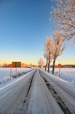 Karla kaplı tarlaların arasından geçen buzlu yol Orebro İsveç 16 Aralık 2022