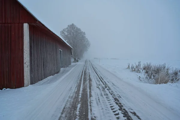 straight winter road beside barn a misty day Kumla Sweden december 16 2022
