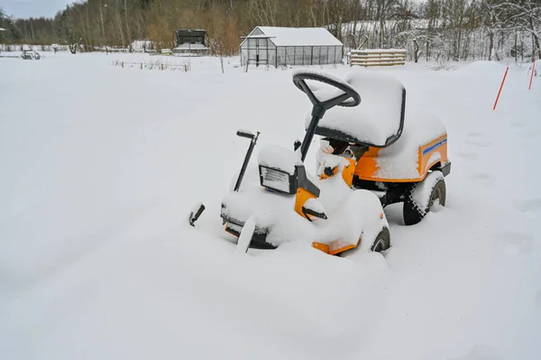 yellow riding lawn mower covered in snow Kumla Sweden january 6 2023