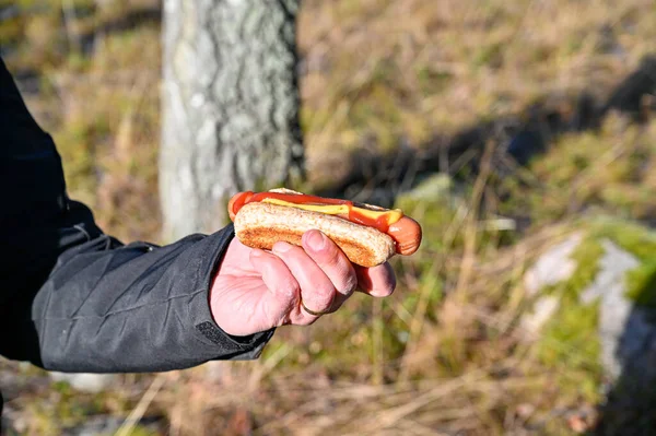 man holding grilled hotdag outdoor in forest Motala Sweden february 4 2023